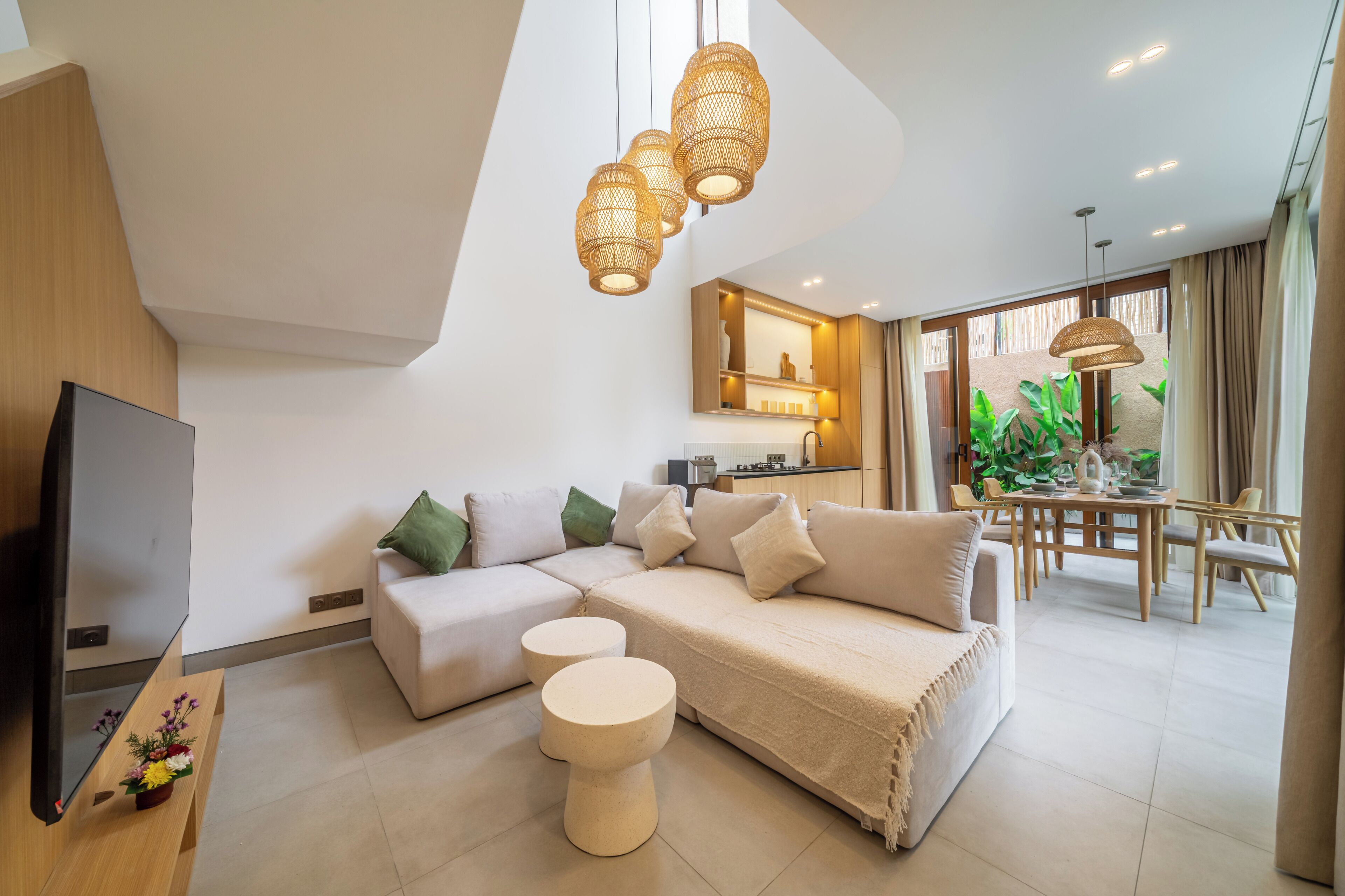 A modern living room with a sectional sofa, a flat-screen TV, and a dining area with a table and chairs.