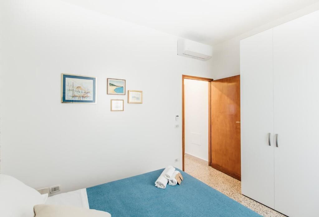 Ein Schlafzimmer mit einem Bett, einem blauen Teppich, einem Kleiderschrank und einer Tür zu einem weiteren Raum.