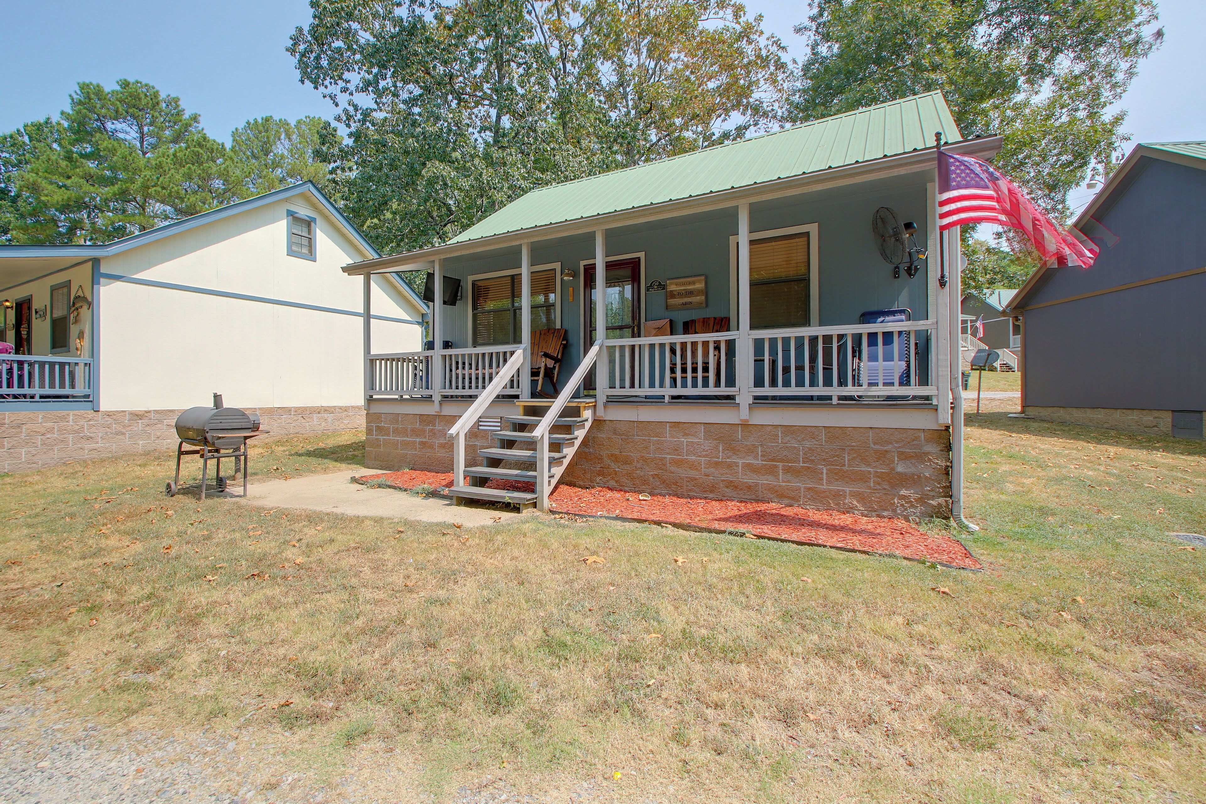 A two-story house with a porch, a flag, and a barbecue grill.