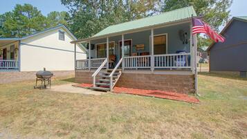 A two-story house with a porch, a flag, and a barbecue grill.