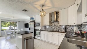 A modern kitchen with white cabinets, a stainless steel refrigerator, an oven, and a dishwasher. - Walk to Water! Boynton Beach Gem w/ Backyard Oasis (Boynton Beach)