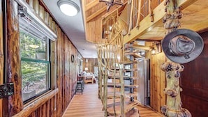 En interiör med träinredning, en spiraltrappa, stora fönster och en rustik inredningsstil.