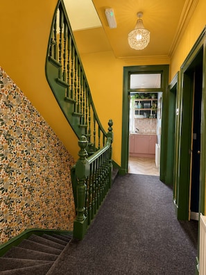Eine Treppe mit grüner Geländer, Teppichstufen und einer Wand mit Muster.