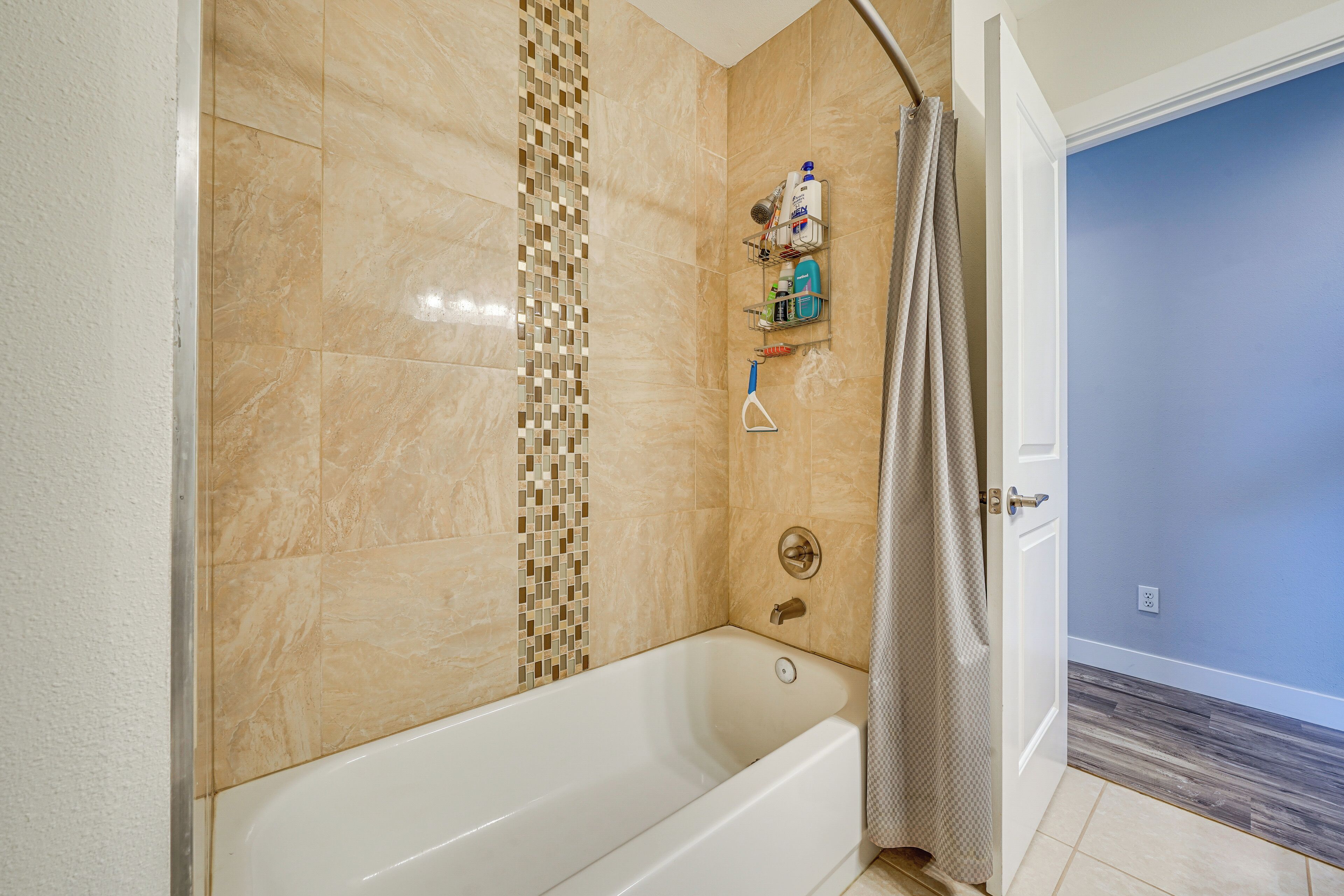 A bathroom with a bathtub, shower, and tiled walls.
