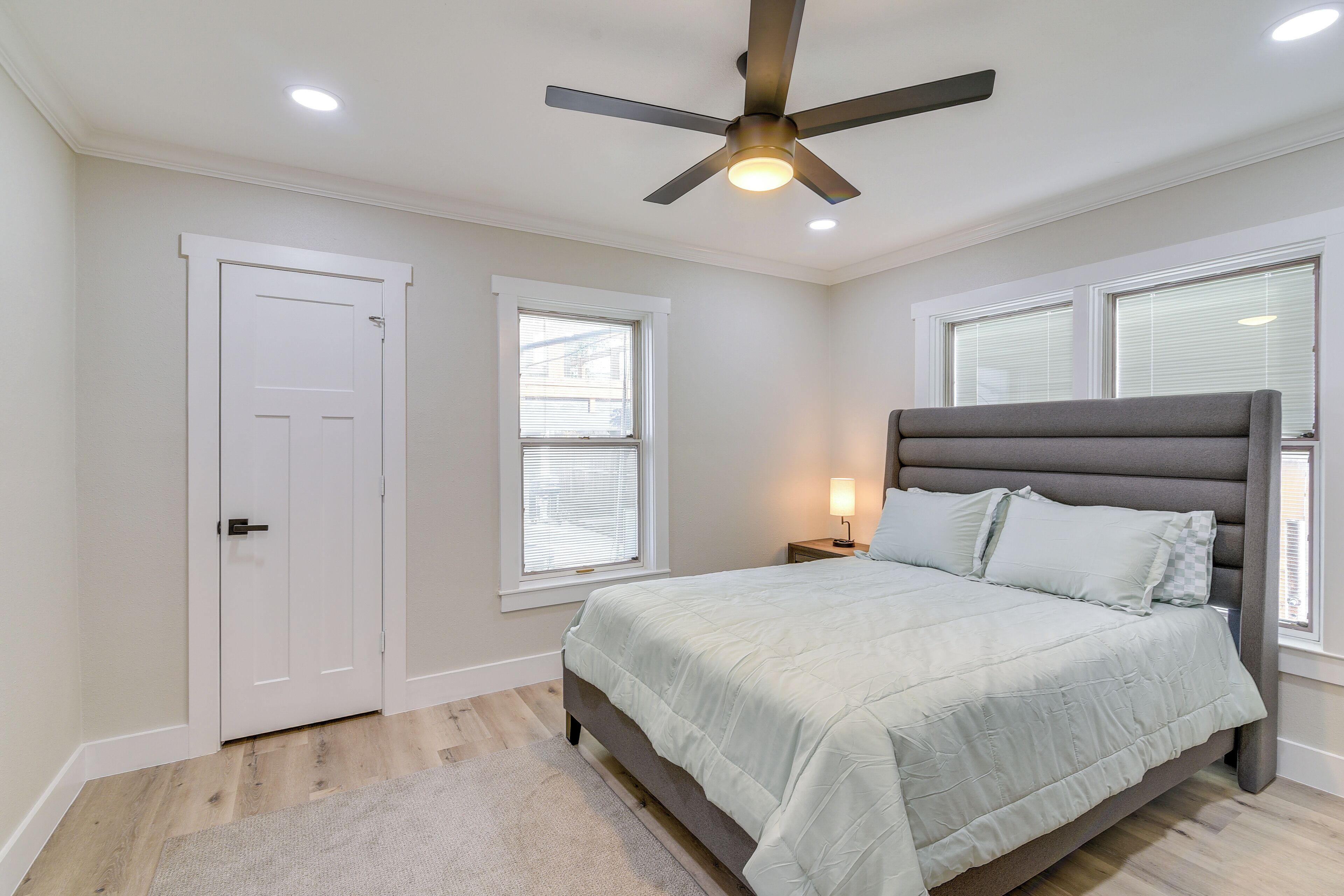 A bedroom with a bed, a ceiling fan, a nightstand, and a window.