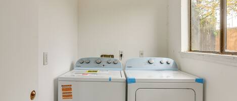 A laundry room with two white washing machines, a window, and a door.