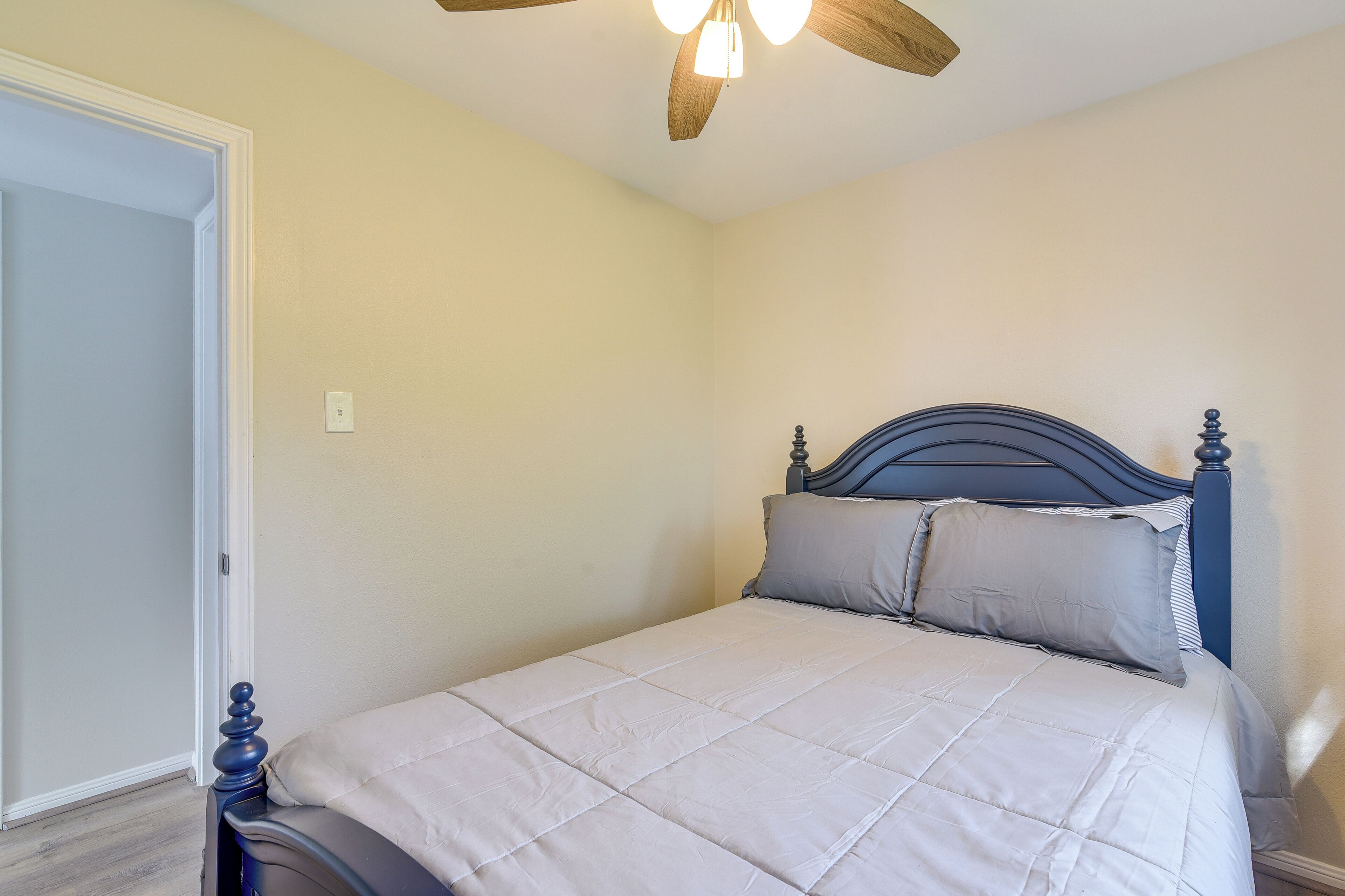 Quarto com cama, ventoinha no teto e porta.