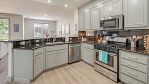 A modern kitchen with grey cabinets, stainless steel appliances, and a large island. - Waterfront Lake Tulloch Townhome Steps From Marina (Copperopolis)