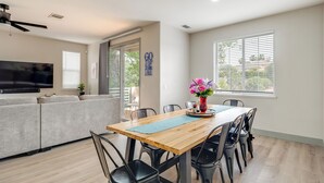 A modern living room with a sofa, TV, dining table with chairs, and a ceiling fan. - Waterfront Lake Tulloch Townhome Steps From Marina (Copperopolis)