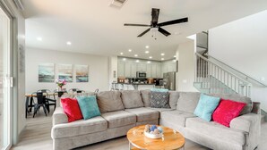 A modern living room with a sectional sofa, a coffee table, and a staircase. - Waterfront Lake Tulloch Townhome Steps From Marina (Copperopolis)