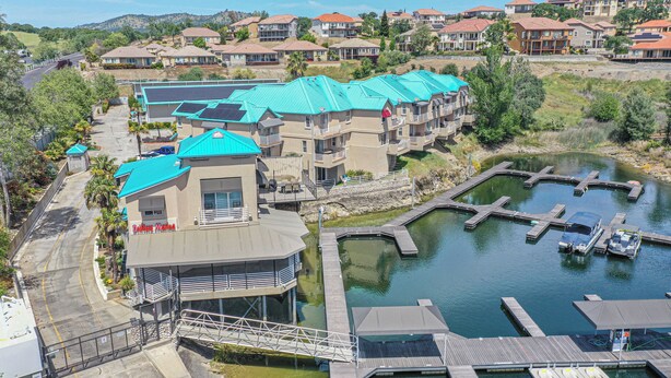 A multi-story hotel with a swimming pool and dock, surrounded by greenery and other buildings. - Waterfront Lake Tulloch Townhome Steps From Marina (Copperopolis)