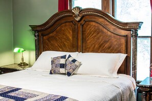 A neatly made bed with a patterned quilt, a wooden headboard, and a nightstand with a lamp.
