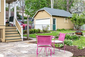 A house with a garage, a porch with steps, and two pink chairs outside.