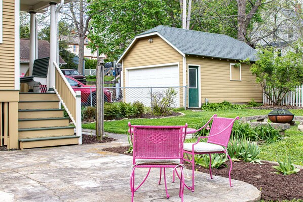 A house with a garage, a porch with steps, and two pink chairs outside.