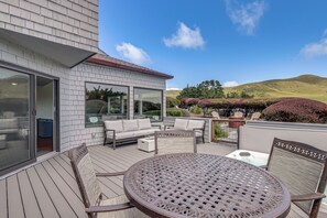 A deck with outdoor furniture, a table, and a view of the surrounding landscape. - Dog-Friendly Haven w/ Stunning Views in Bodega Bay (Bodega Bay)