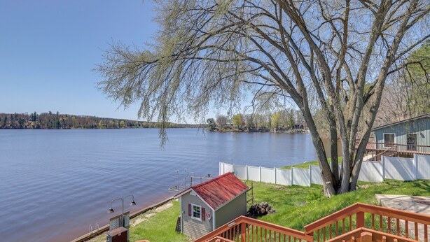 A lakeside property with a small shed, a wooden deck, and a view of the lake. - Waterfront Cabin w/ Boat Slip & Views in Croton! (Newaygo)