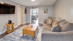 A living room with a sofa, coffee table, TV, and a door labeled 'Friends.' - Waterfront Cabin w/ Boat Slip & Views in Croton! (Newaygo)