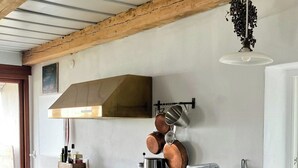Eine Küche mit Holzausstattung, einem Edelstahl-Spülbecken, hängenden Töpfen und einer Kaffeemaschine.