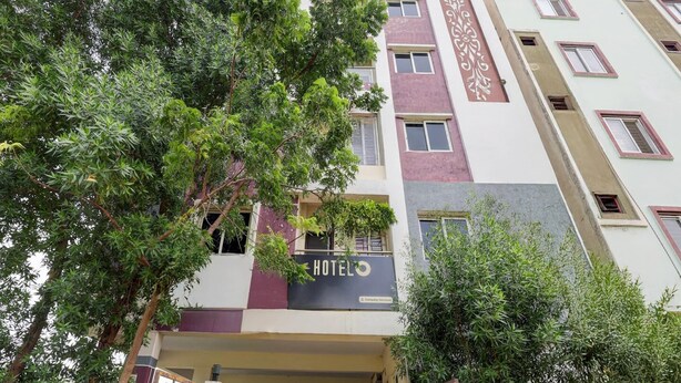 A multi-story hotel with a prominent 'HOTEL' sign, a gated entrance, and a balcony with a railing.