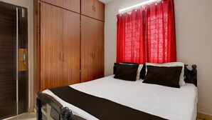 A bedroom with a bed, a wardrobe, and a window with curtains.