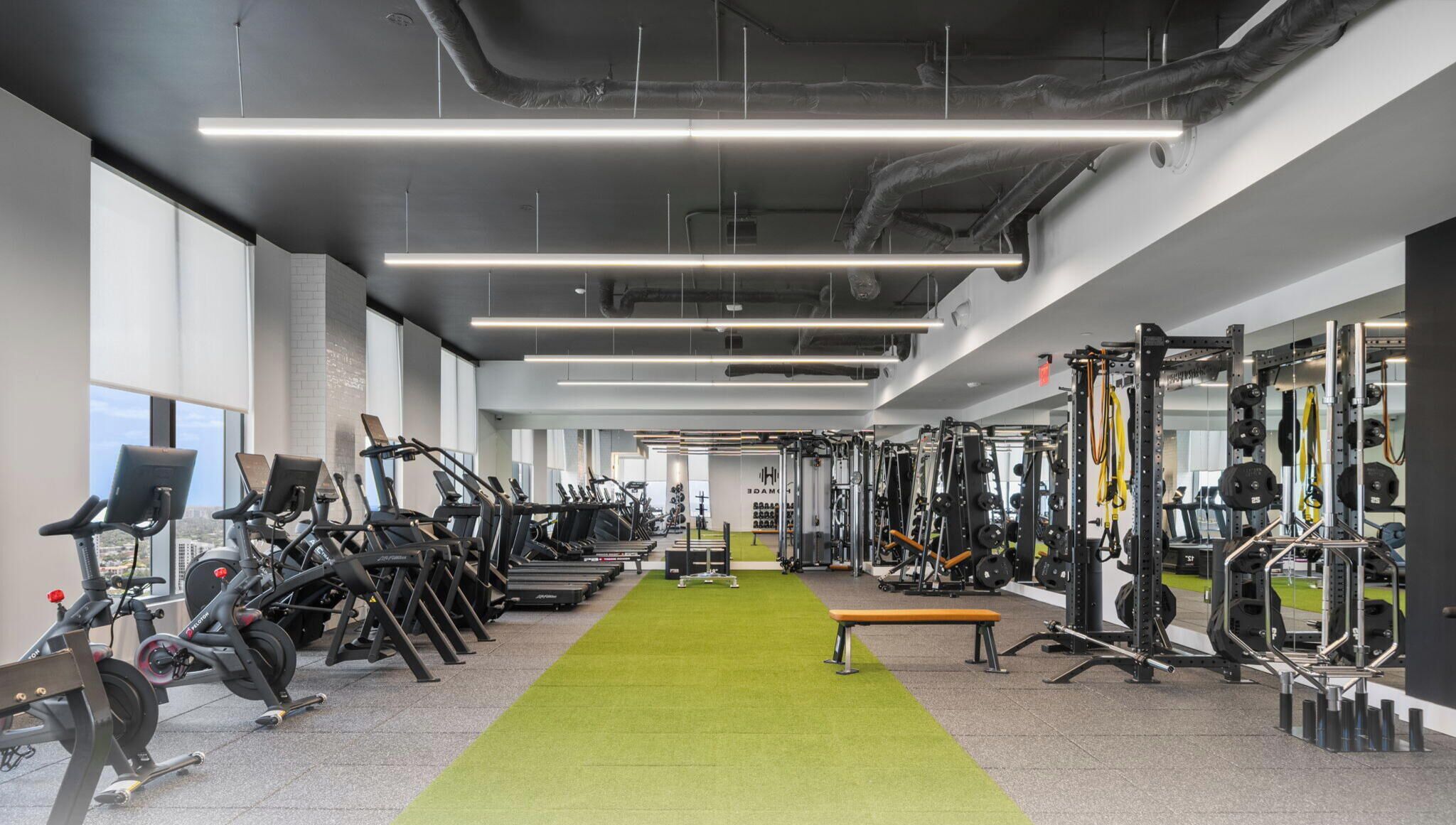 A gym with treadmills, weight machines, and a green carpet.