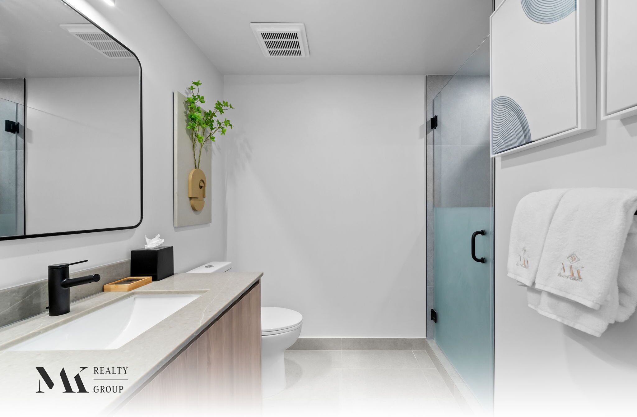 Un baño moderno con un espejo grande, un lavabo, un inodoro y una zona de ducha.