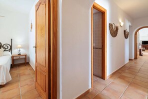 Une chambre d’hôtel comprenant un lit, une table de chevet, une lampe, une armoire en bois et une salle de bain avec douche.