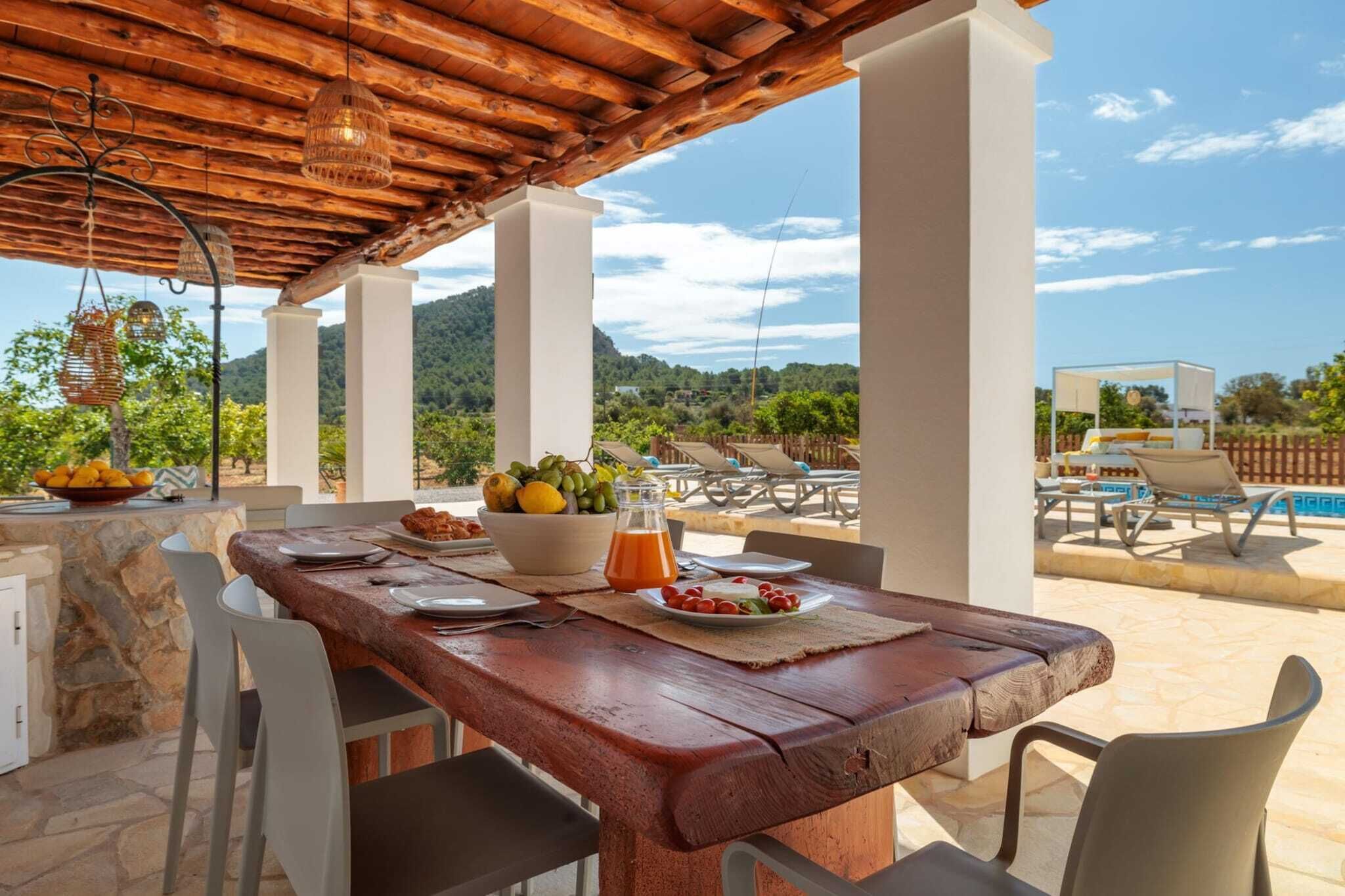 An outdoor dining area with a wooden table, chairs, and a view of the mountains.
