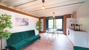 A modern living space with a green sofa, a dining table, and a kitchen area. - The Industrial Apartments|2BBK|NS (Antwerp)