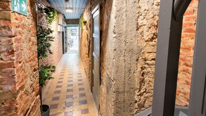 A narrow corridor with brick walls, a checkered floor, and hanging plants. - The Industrial Apartments|2BBK|wifi|NS (Antwerp)