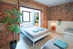 A room with a bed, a potted plant, a fireplace, and a brick wall. - The Industrial Apartments 2BBK|Non Smk|Wi-fi (Antwerp)