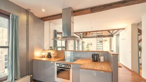 Eine moderne Küche mit Einbauofen, Edelstahl-Dunstabzugshaube und Holz Arbeitsplatten.