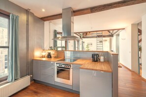 Una cocina moderna con horno empotrado, campana extractora de acero inoxidable y encimeras de madera.