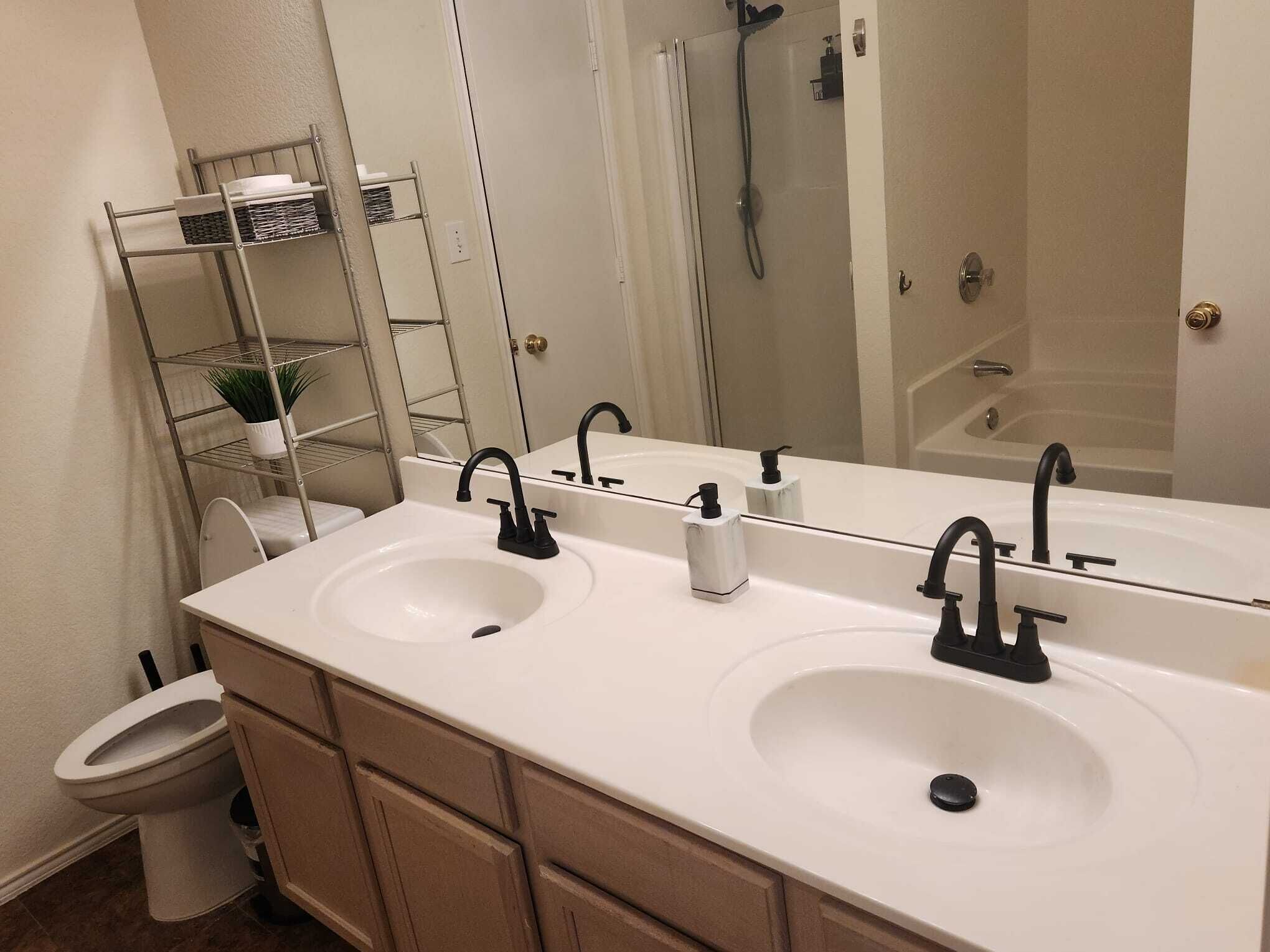 A bathroom with two sinks, a toilet, a shower, and a large mirror.