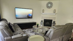 Una sala de estar con sofá, televisor, chimenea y un adorno en la pared.