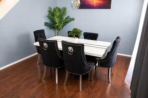 Un espace repas avec une table blanche et des chaises noires dotées de dossiers décoratifs.