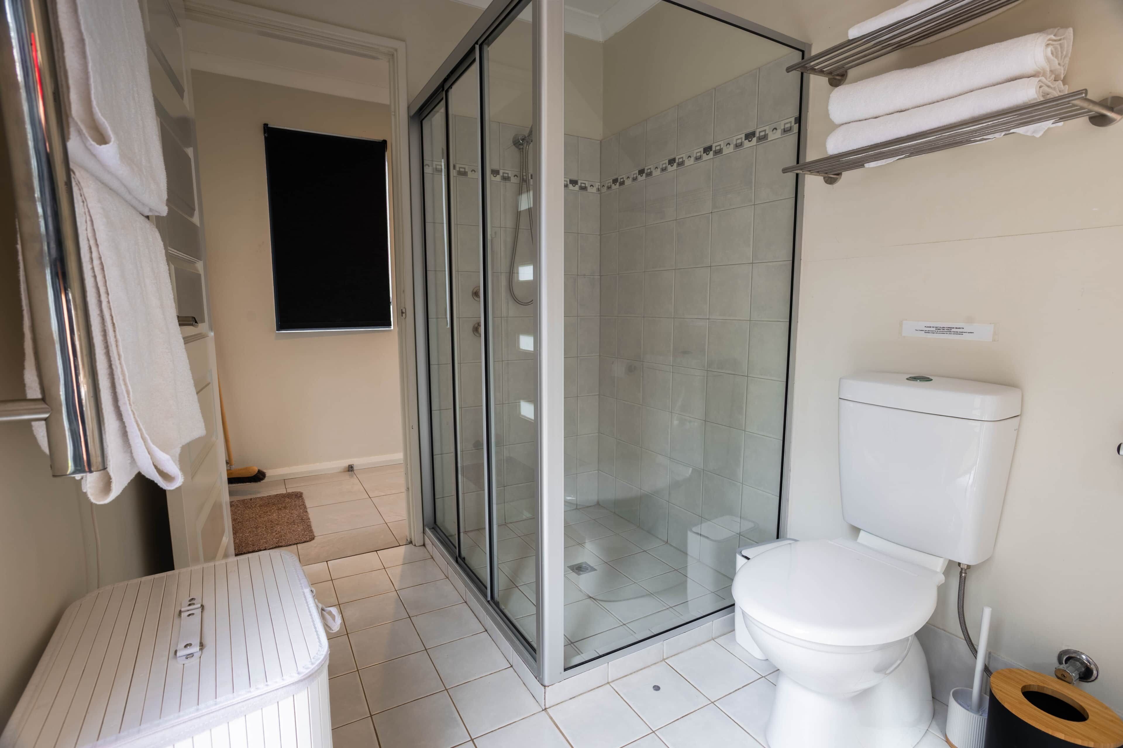 A bathroom with a toilet, a glass-enclosed shower, and a towel rack.