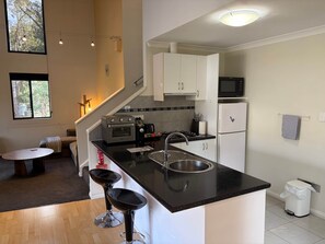 A modern kitchen with a central island, built-in oven, and stainless steel appliances.