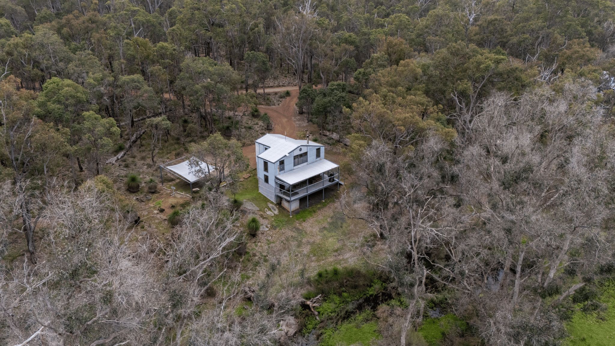 Una casa moderna de dos pisos rodeada de un bosque denso.