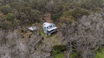 Una casa moderna de dos pisos rodeada de un bosque denso.