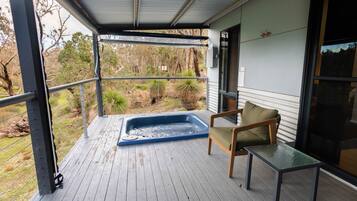Un espacio al aire libre techado con un jacuzzi, una silla y una mesa.
