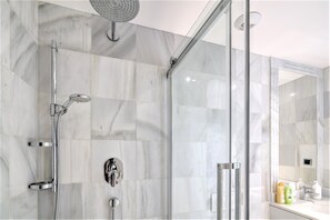 Ein modernes Badezimmer mit einer Duschkabine aus Glas, einer Handbrause und einem wandmontierten Wasserhahn.