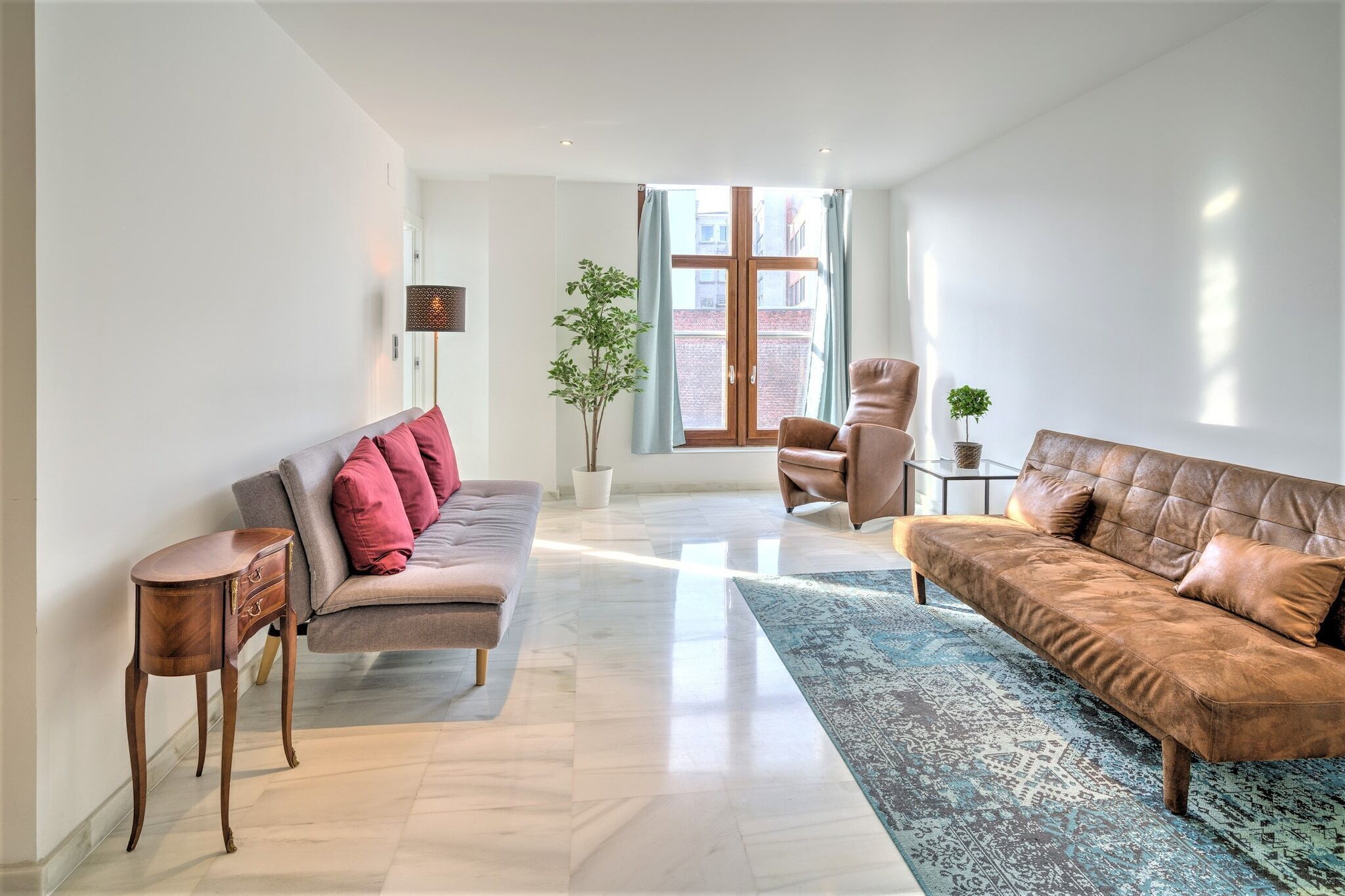 A modern living room with a sofa, armchair, and a small table.
