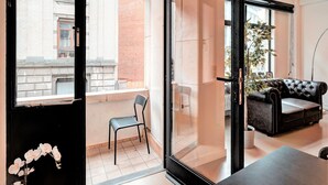 A modern living room with a glass door leading to a balcony, a leather sofa, a dining table, and a potted plant. - Spacious apartment in heart of Antwerp (Antwerp Center)