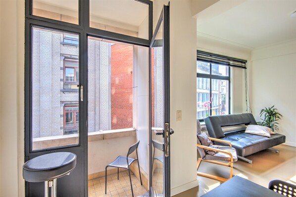 Ein modernes Apartment mit einem Balkon, einer Couch, einem Sessel und einem kleinen Tisch.