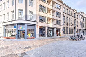 Rua com edifícios, uma loja com placa e bicicletas estacionadas.