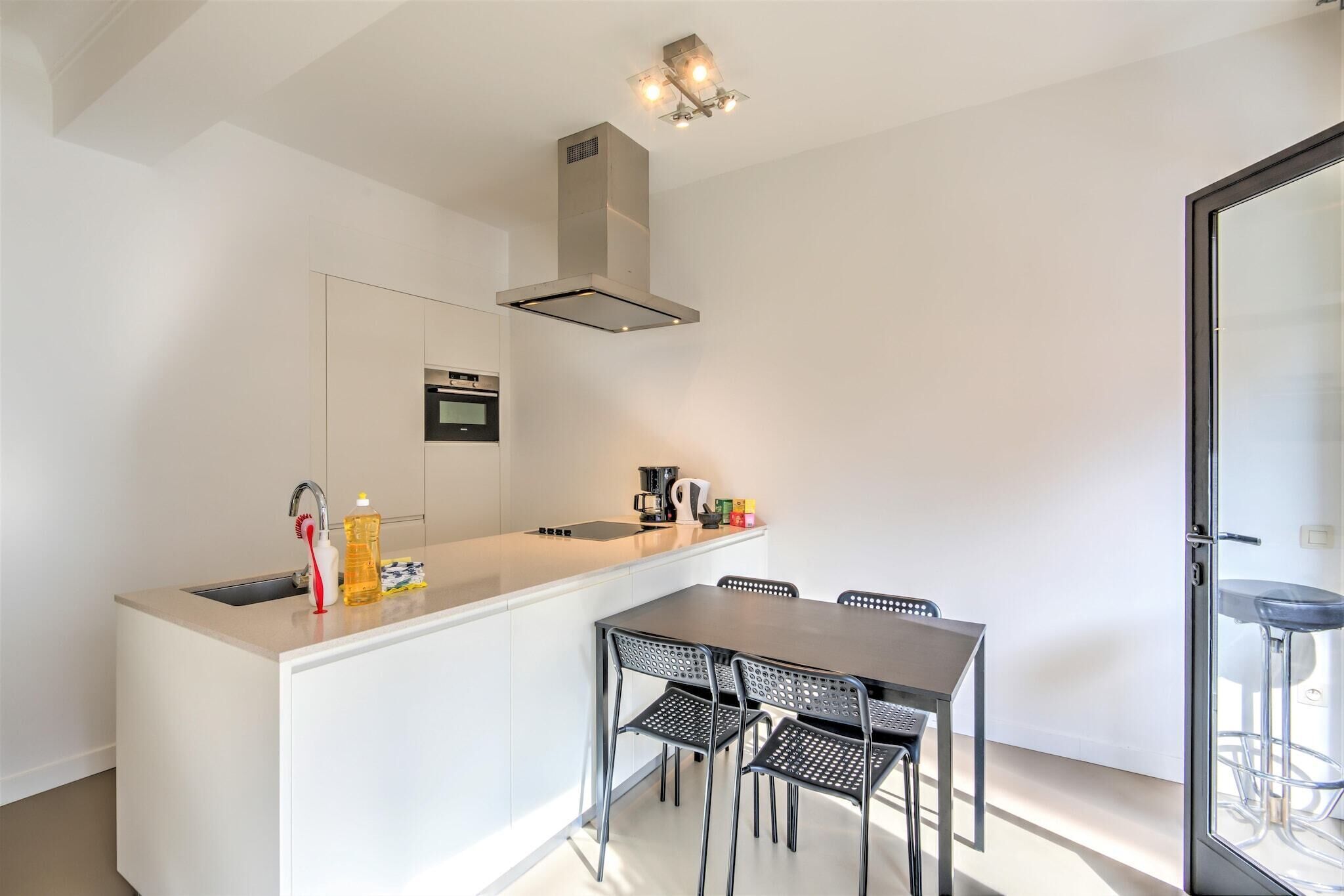 A modern kitchen with a central island, a dining table with chairs, and a built-in oven.