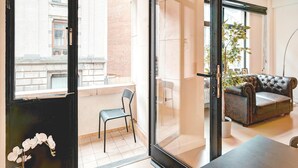 A modern living room with a sofa, a dining table, a chair, and a balcony with a view of buildings. - Welcoming Antwerp Relaxing Stay (Antwerp Center)