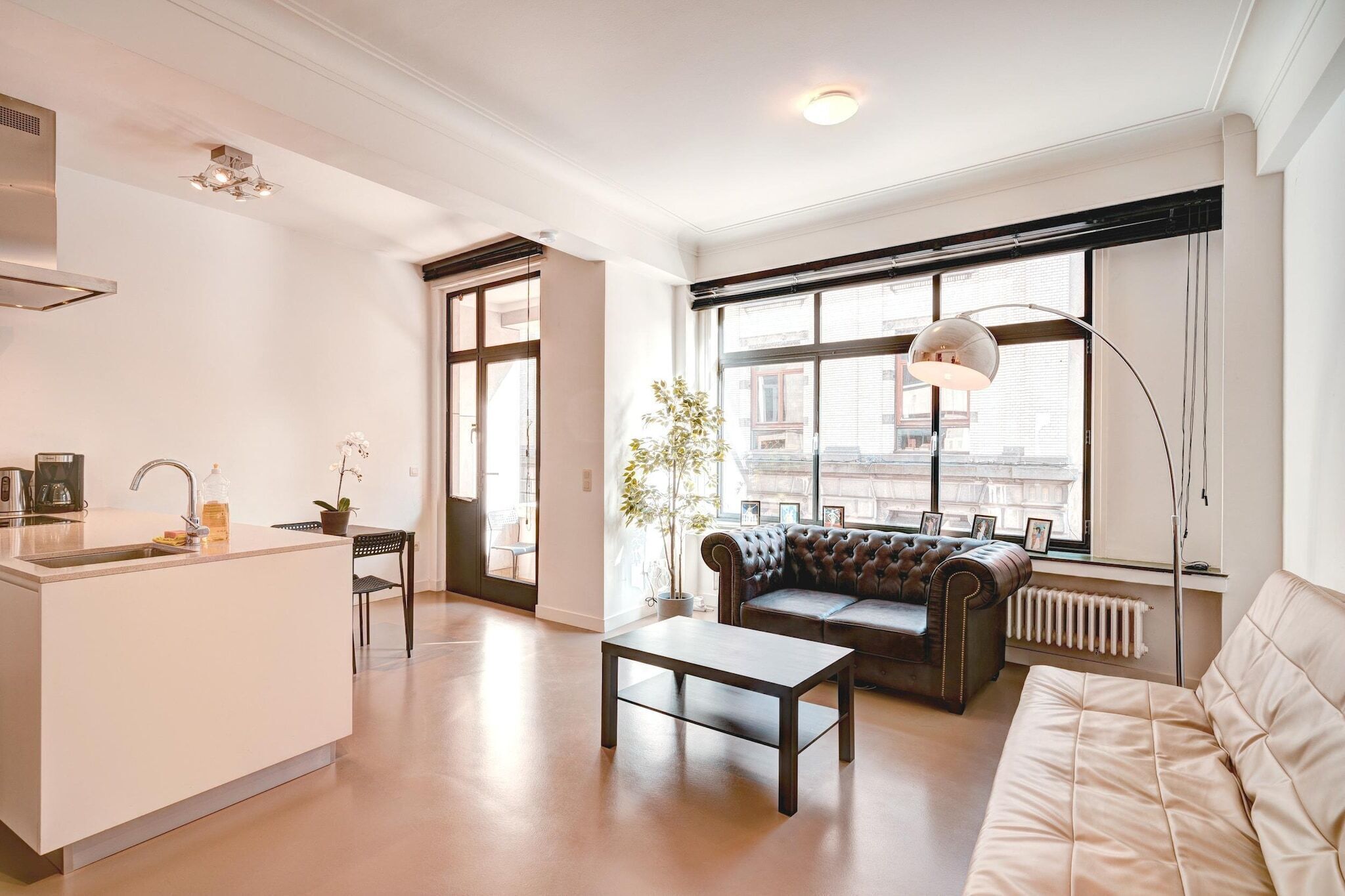 A modern living room with a sofa, coffee table, and a large window with a view of buildings.