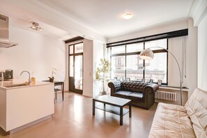 Un salón moderno con sofá, mesa de centro y un amplio ventanal con vistas a edificios.